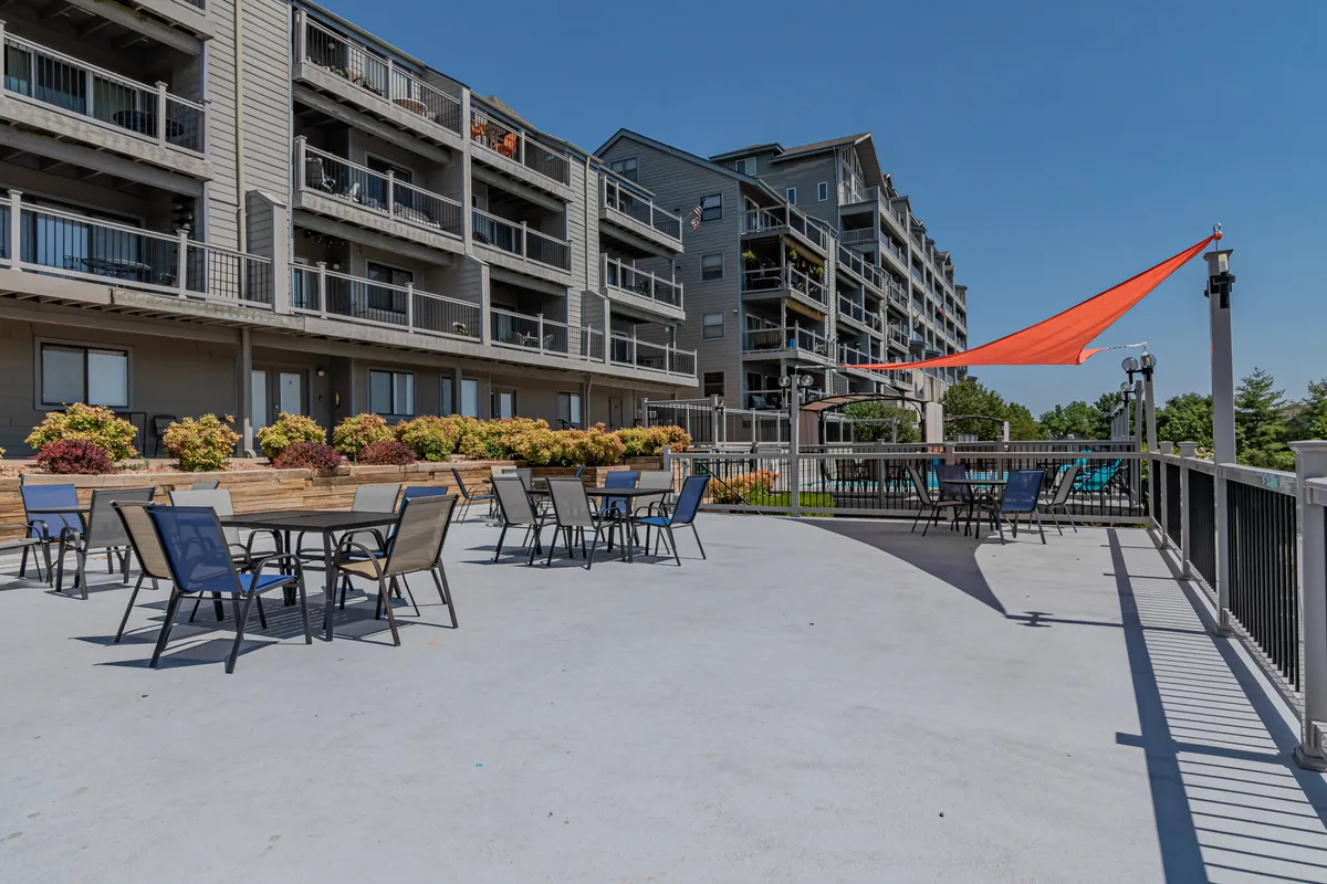 This image showcases an inviting outdoor seating area with a shade sail, surrounded by flower beds and balconies. The setting suggests communal spaces for relaxation, outdoor dining, and family activities, signaling the shared amenities included in the property experience.