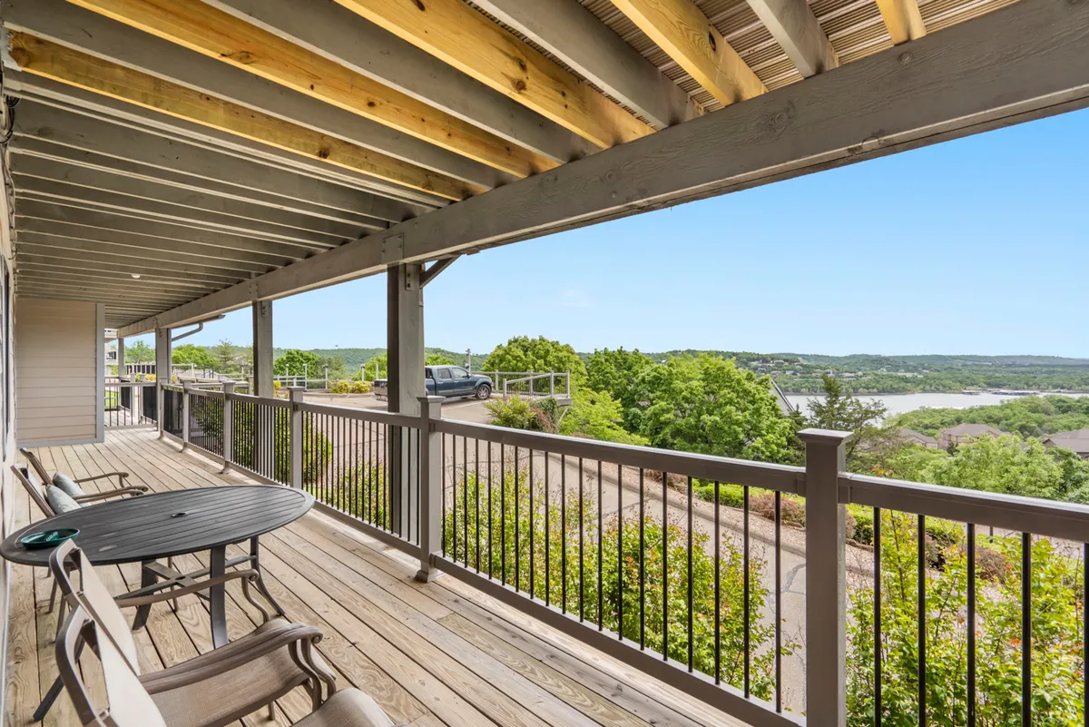 An inviting deck with comfortable outdoor furniture overlooks panoramic natural scenery, including tree-lined shores and gentle hills. The setting is serene and perfectly suited for starlit evenings or quiet moments by the lake.