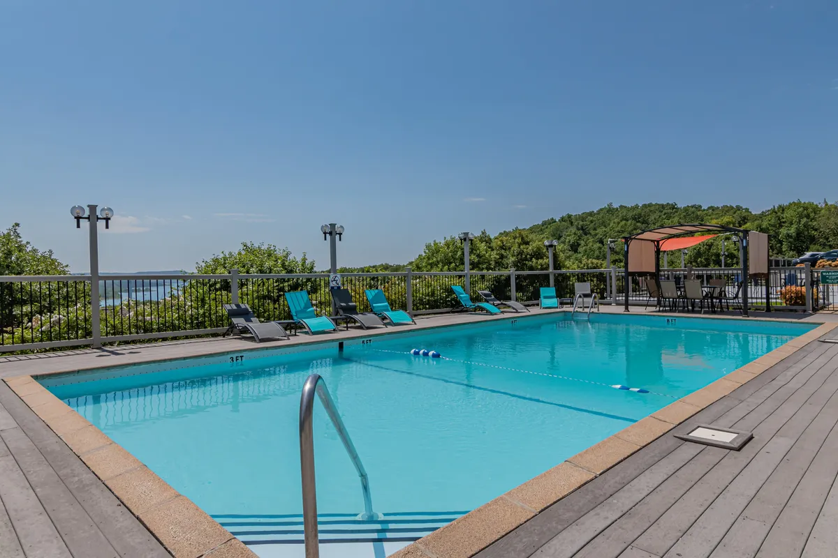 A lively outdoor swimming pool area with lounge chairs, a poolside cabana, and landscaped surroundings. The scene is set for sunbathing, socializing, or relaxing after a day of adventures, with plenty of space for friends to gather and enjoy leisure time together.