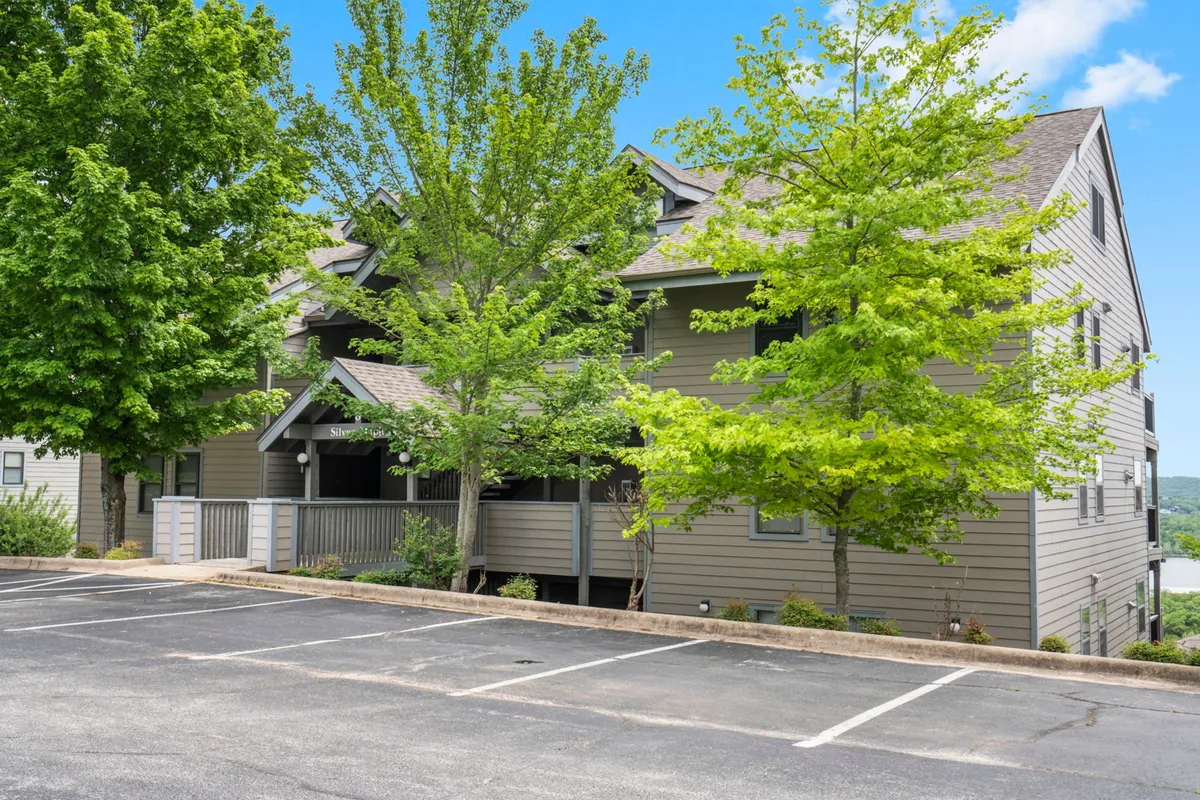 This exterior image captures the condo building’s facade surrounded by lush green trees and a peaceful parking area. The welcoming outdoor environment hints at the natural beauty of the area and the sense of community within the resort complex.