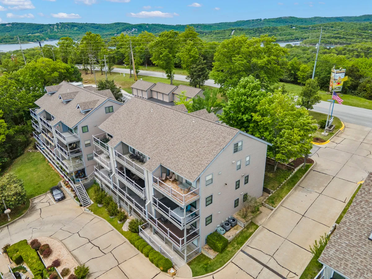 This image highlights the exterior of the multi-unit building surrounded by a green landscape and a parking area. The scene suggests accessibility, convenience, and a tranquil atmosphere, setting the context for guests arriving at Silver Maple 311. The view hints at nearby water and open space, reinforcing the sense of relaxation and value in the Branson area.