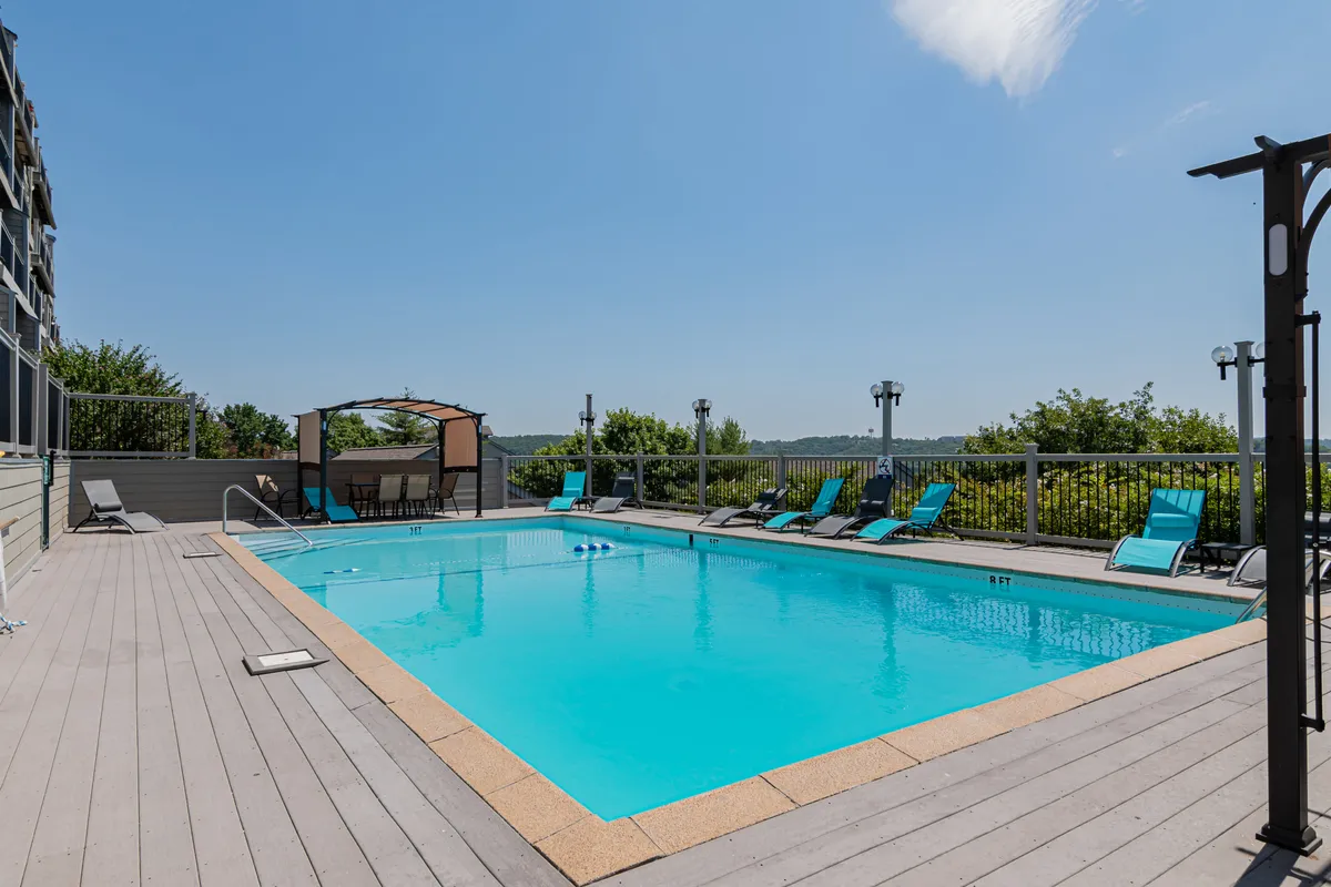 This image features a sparkling outdoor swimming pool surrounded by lounge chairs and a cabana, set against a relaxed backdrop that suggests sunny days and social gatherings. The setting is perfect for swimming, sunbathing, and enjoying the outdoors, especially during the resort's seasonal pool opening.